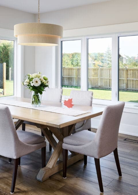 A spacious and elegant dining room featuring a large, custom wood dining table surrounded by comfortable seating.