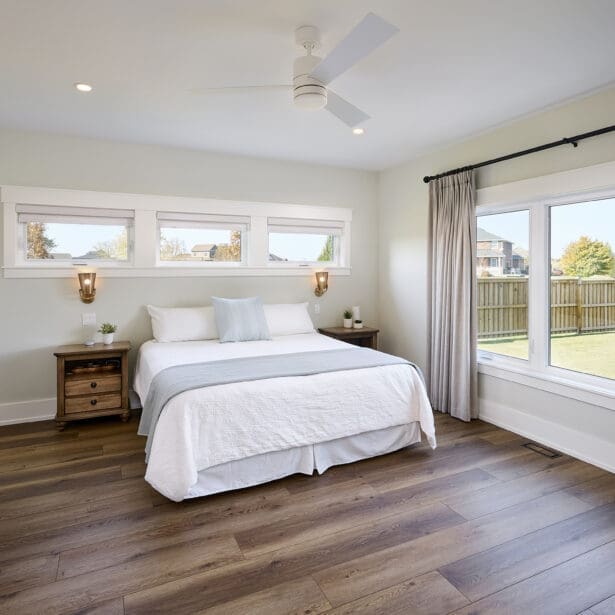 A spacious and tranquil primary bedroom featuring natural wood accents and soft, neutral tones