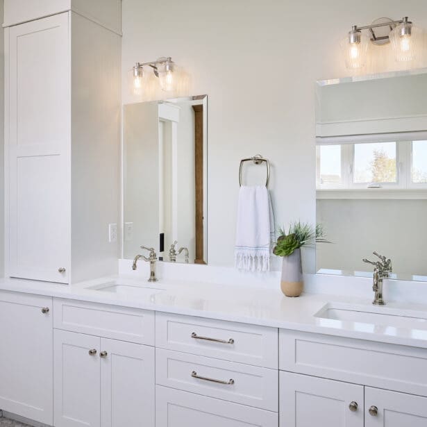 A stylish primary ensuite featuring crisp white cabinetry that offers a clean, modern look. The cabinets provide ample storage while maintaining a bright and airy atmosphere, complemented by sleek hardware and a neutral color palette.