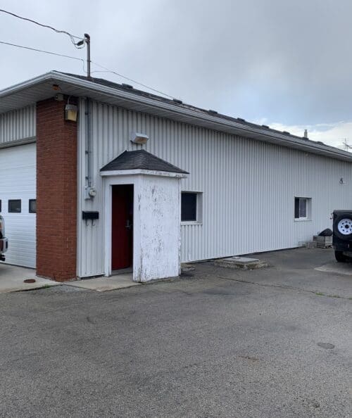 Front view of the old firehall before renovation, featuring arched garage bays and aged masonry.