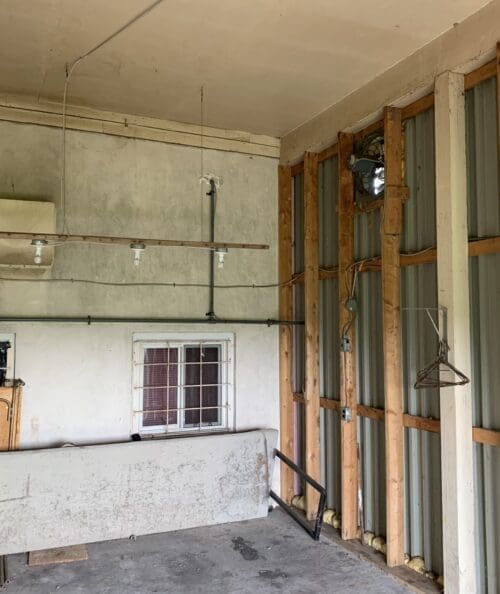 Interior of the old firehouse showing exposed brick walls, concrete floors, and remnants of equipment bays